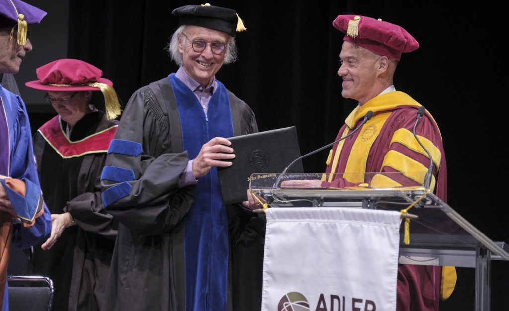 Man receiving a degree on stage at a university commencement ceremony
