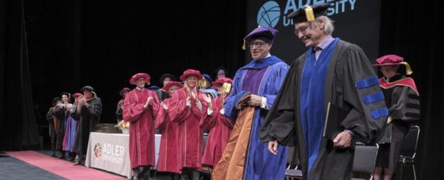 Donald Honourary Degree 2 Two men walk off stage in robes and Adler University's commencement ceremony for their class of 2019