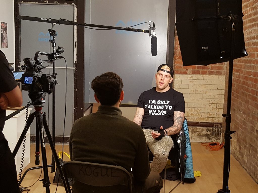 a man sitting on a chair being interviewed by a camera crew
