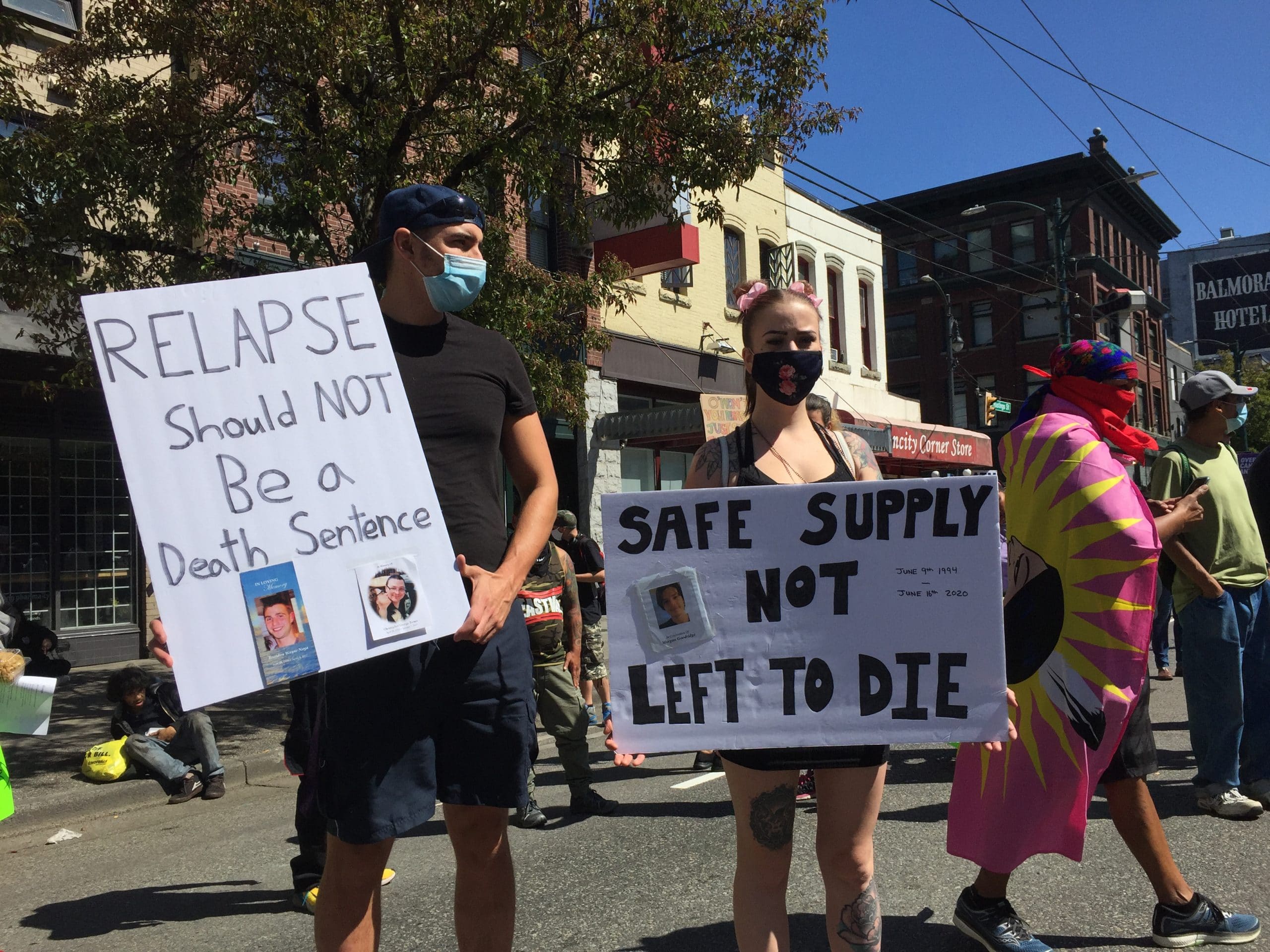 Two people holding signs at a Downtown Eastside protest and rally in Vancouver