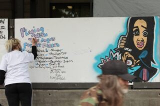 A woman writing a message on a billboard during International Overdose Awareness Day