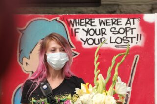 Woman standing with flowers against a billboard