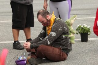 Man sitting cross legged on the sidewalk with his head down