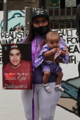 Indigenous woman holding a baby and a photo of a family member or friend