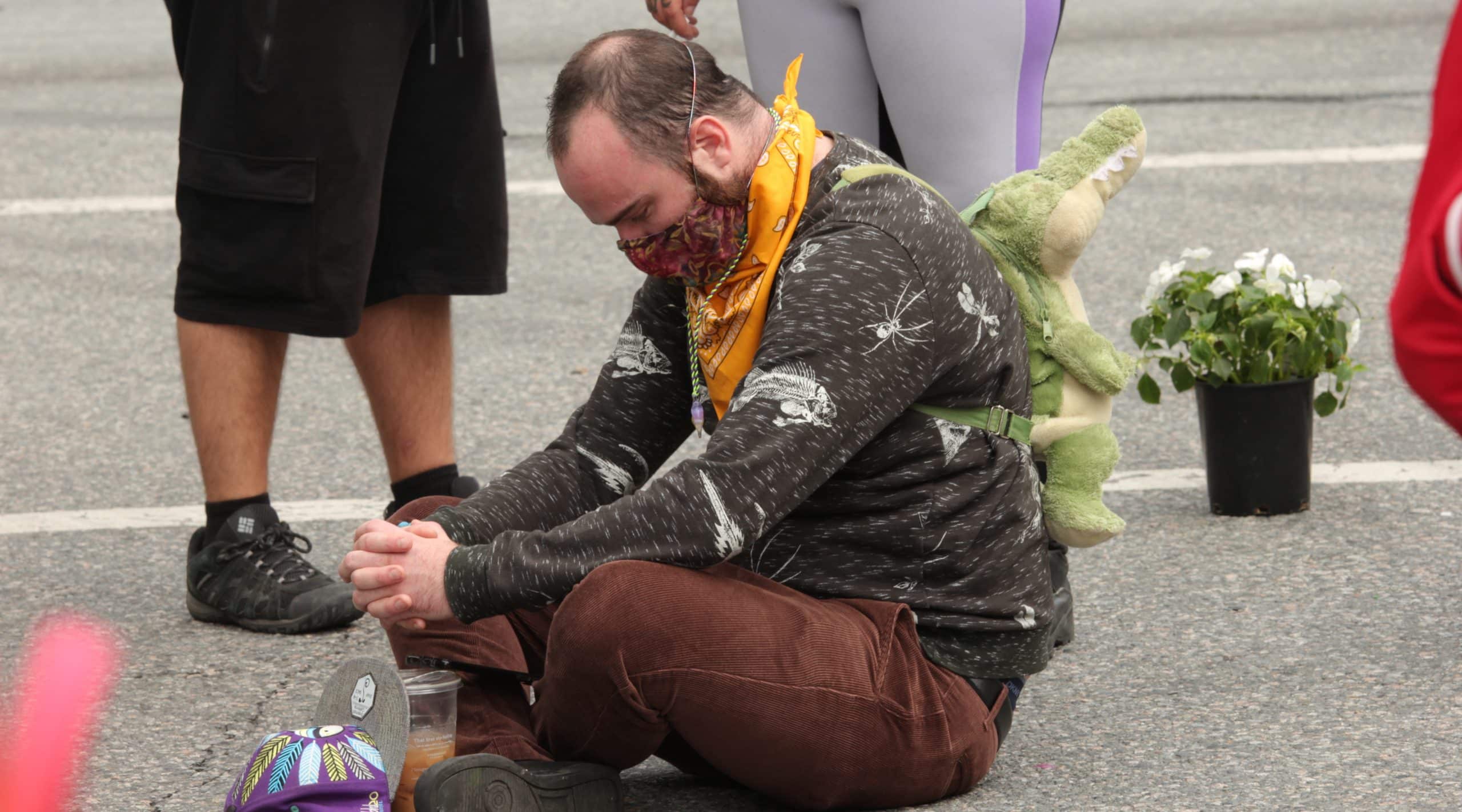 A mourner sits on the ground at a rally in Vancouver
