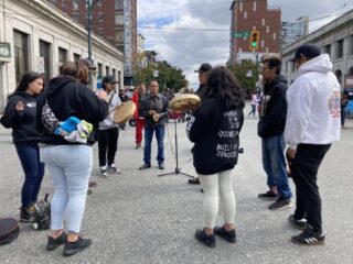Drummers in a circle playing at a rally in the Downtown Eastside