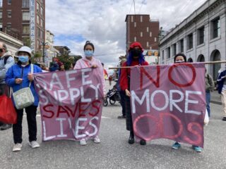 Four people holding a pink banner at protest