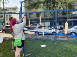 A woman pinning a wooden feather on a fence