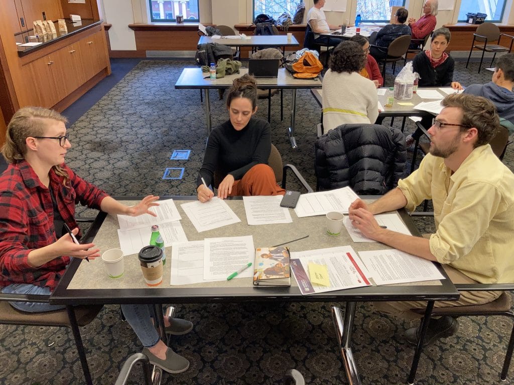 Three members of CDPC staff at a table in discussion during group exercise